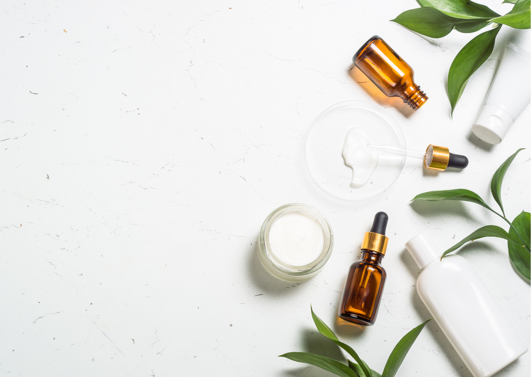 Fioles cosmétiques et feuilles sur fond blanc